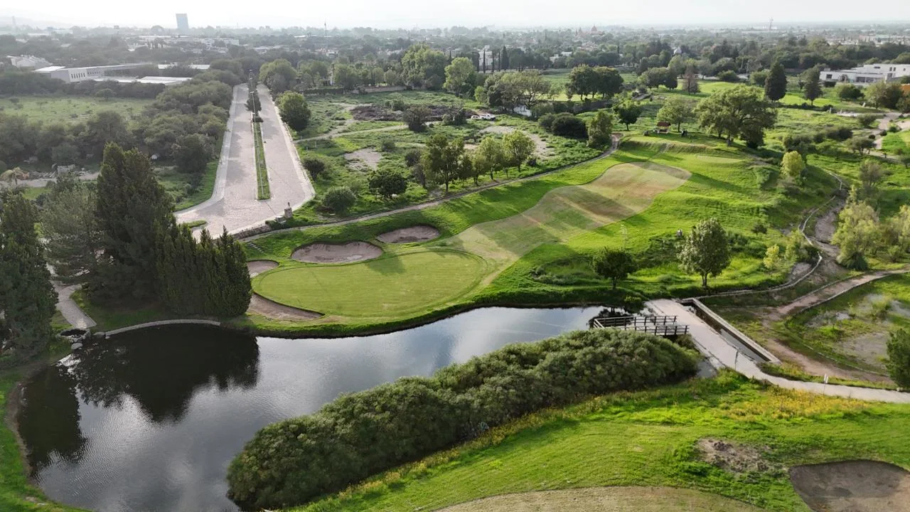 Vista aérea del campo de golf con lago y áreas verdes.