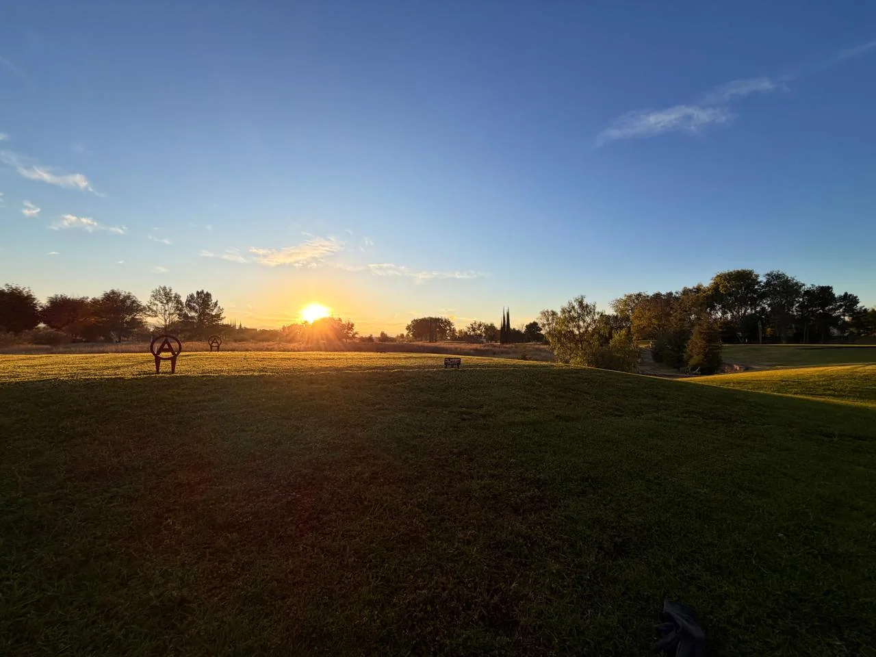Campo de golf al atardecer con sol bajo.
