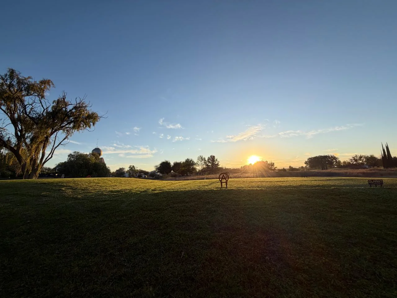 Campo de golf al atardecer con horizonte cálido.